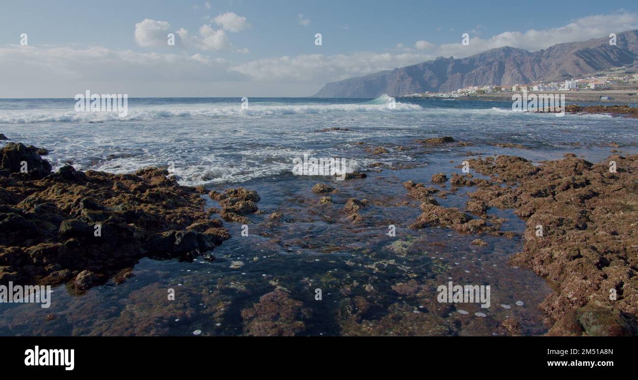 Schizzi di onde. Spiaggia vulcanica rocciosa nera con pietre laviche nere. Puerto de la Santiago, Tenerife. Punta Blanca o Punta Juanita - il posto migliore Foto Stock