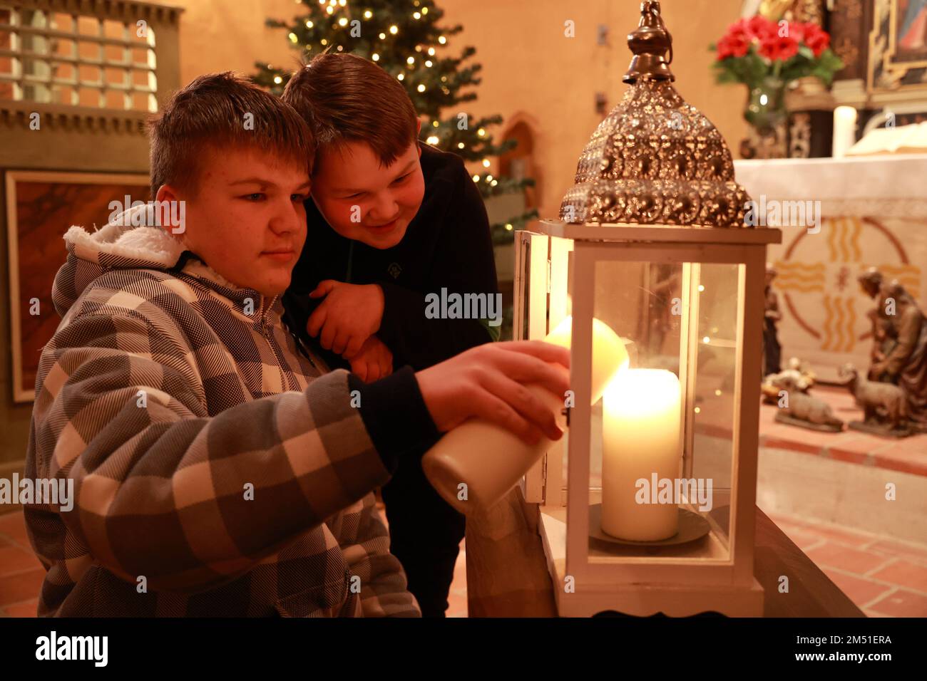 Beyendorf, Germania. 24th Dec, 2022. Felix (l) e Matti recuperano la luce della pace dalla chiesa protestante decorata in modo fantastico Chiesa di Pietro durante una celebrazione della natività dei bambini. Le parrocchie della Chiesa Protestante nella Germania Centrale (EKM) si aspettano circa mezzo milione di visitatori per più di 4.000 Vespri natalizi e presepi. Credit: Peter Gercke/dpa-Zentralbild/ZB/dpa/Alamy Live News Foto Stock