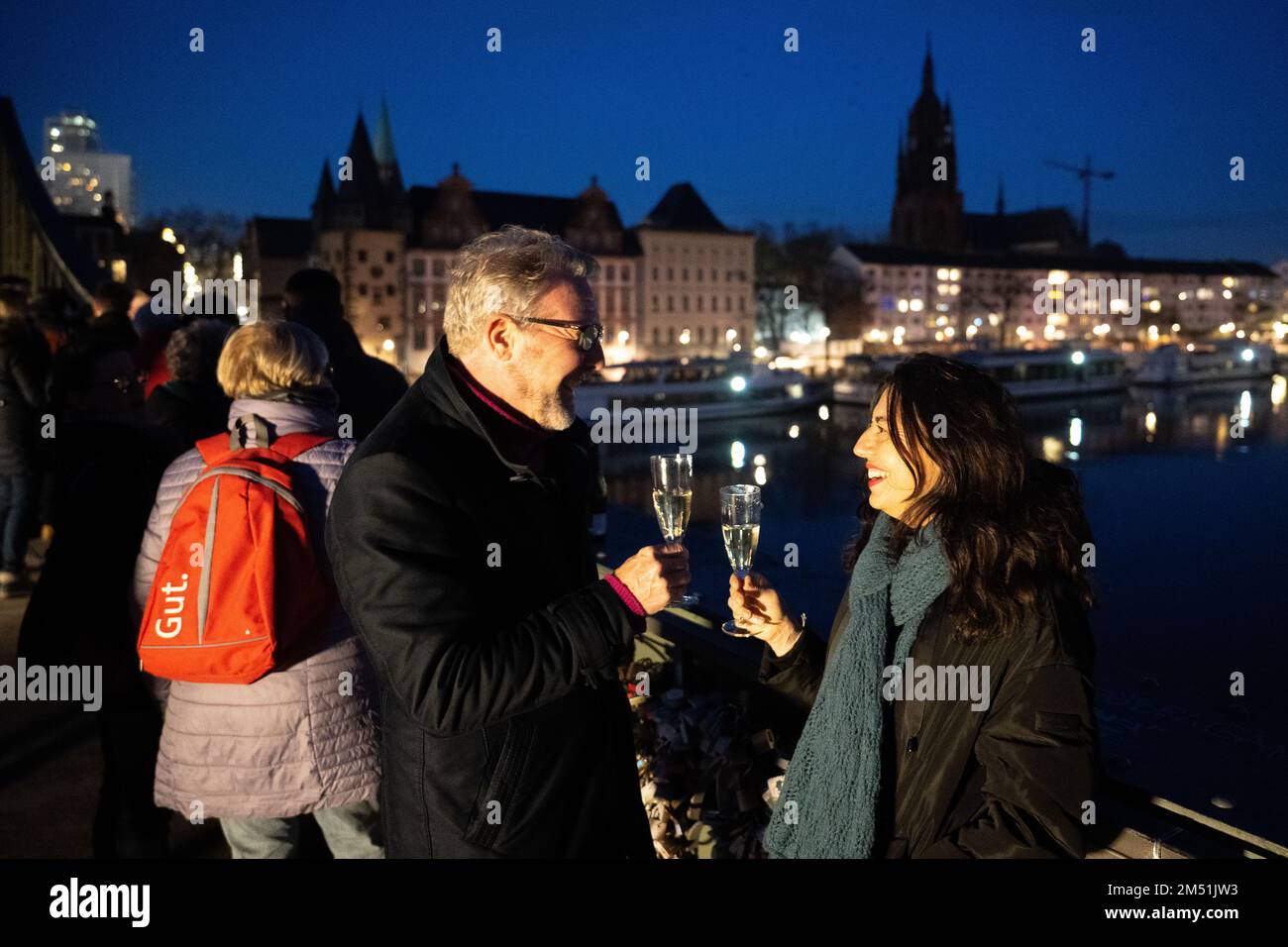 24 dicembre 2022, Assia, Francoforte sul meno: Marc e Raffaella brindano durante il "Grande Ringing della città di Francoforte". La cattedrale imperiale di San Bartolomeo può essere visto sullo sfondo. Il concerto di campana di dieci chiese di Francoforte nel centro della città è tradizionalmente suonato prima delle vacanze in alta chiesa. Foto: Sebastian Gollnow/dpa Foto Stock