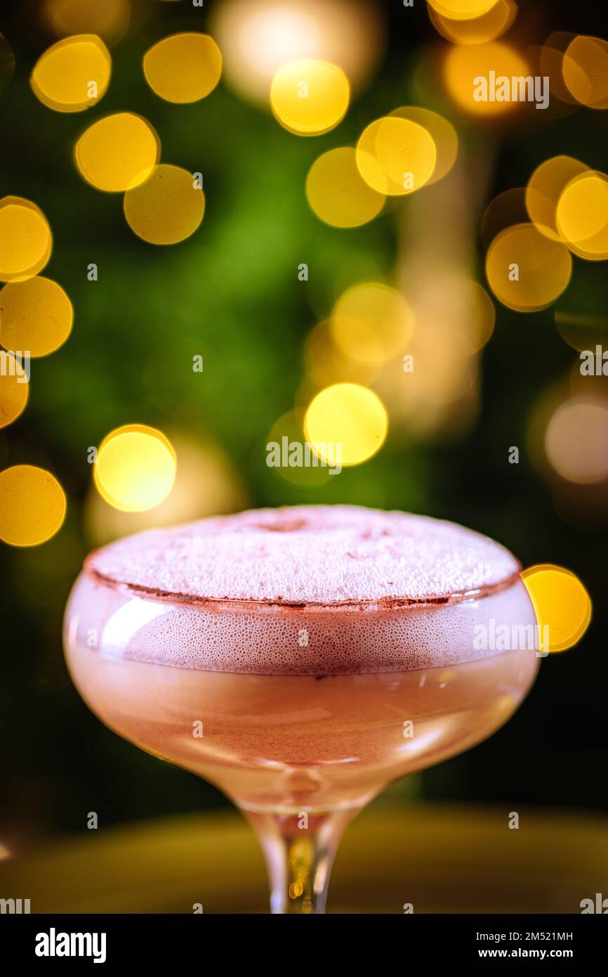 Cocktail con caffè espresso in vetro coupé collocato sul vassoio dorato Decorazione di Natale con luci sullo sfondo. Atmosfera di festa di nuovo anno. Foto Stock