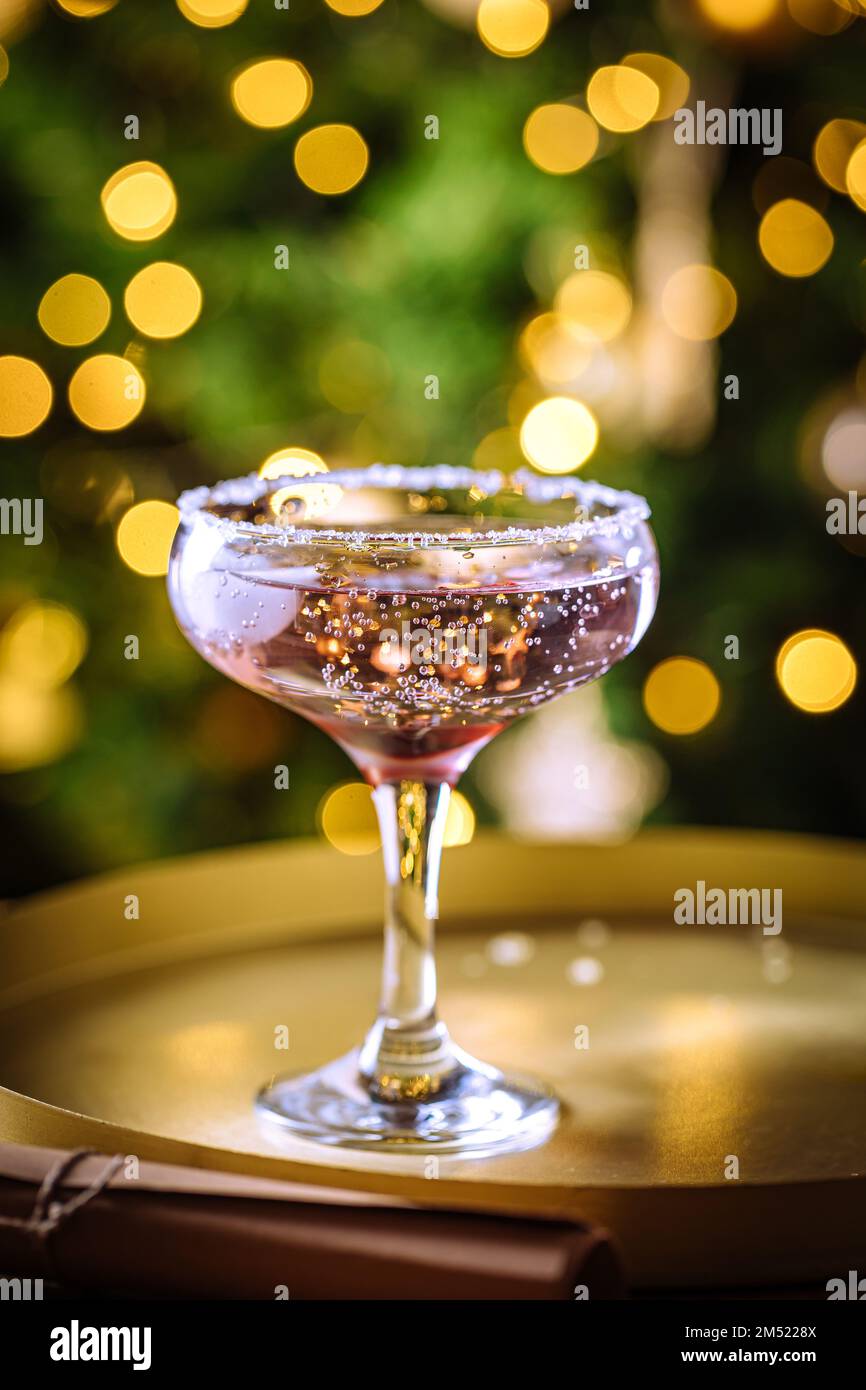 Cocktail di rose in coupé con acqua frizzante. Luci di Natale sullo sfondo. Foto Stock