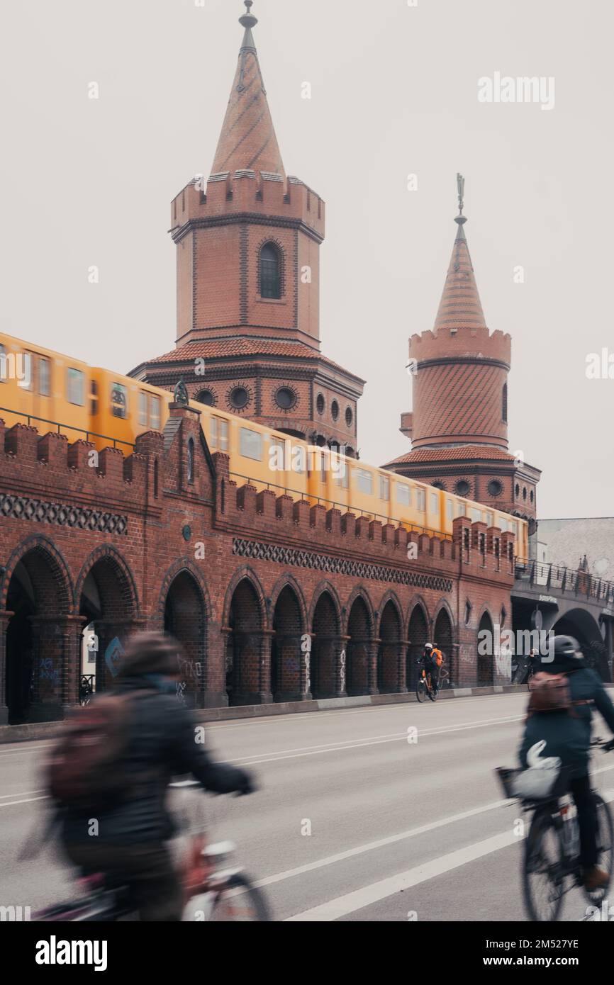 Un movimento verticale sfocato di persone che attraversano il ponte Oberbaumbrucke a Berlino in bicicletta in una giornata di nebbia Foto Stock