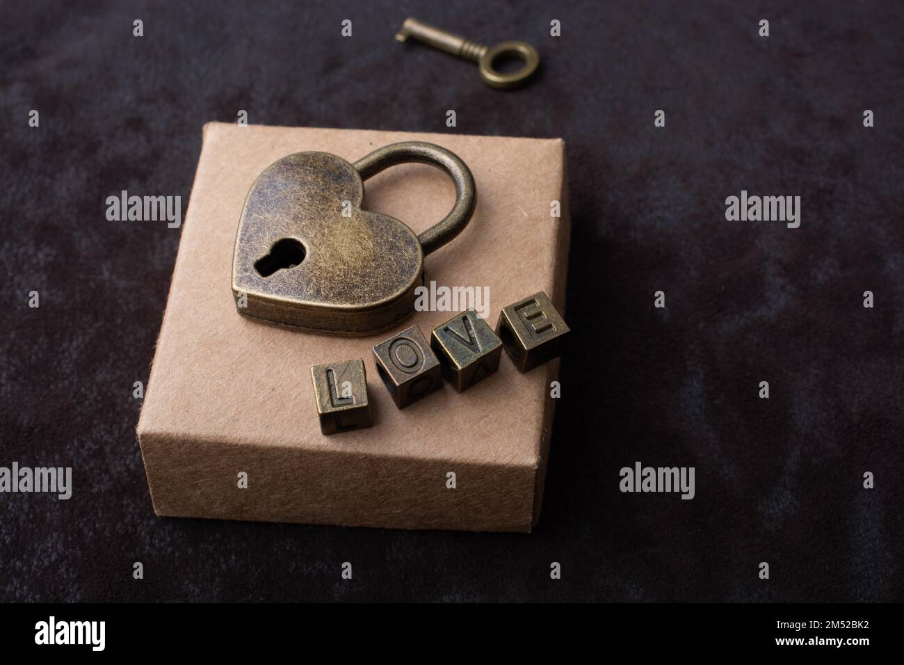 Lucchetto a forma d'amore, chiave e testo d'amore posto sulla scatola Foto Stock