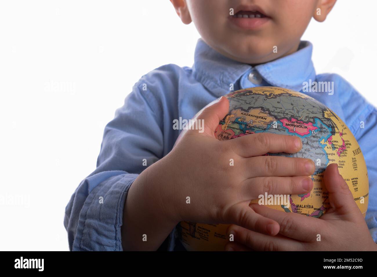 Il bambino con la maglietta blu tenendo un globo in mano su sfondo bianco Foto Stock