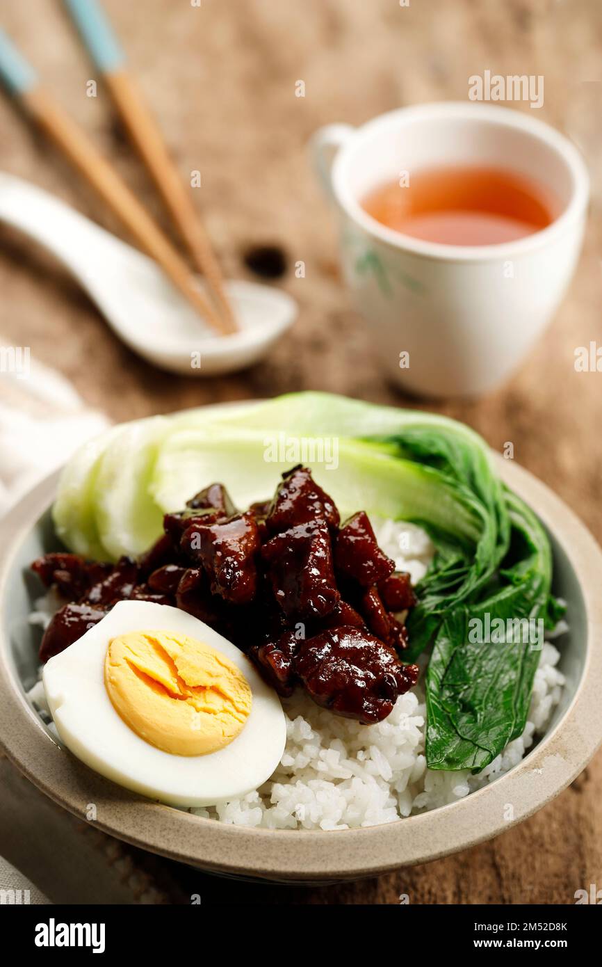 Primo piano maiale brasato taiwanese su riso con GGG mezzo bollito e Pak Choi. Su tavola di legno Foto Stock