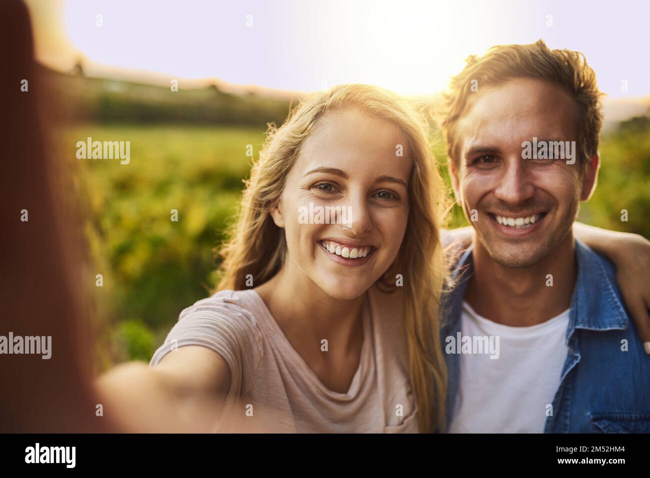 Voglio che questi momenti durino per sempre. una giovane coppia che prende un selfie insieme al loro terreno agricolo sullo sfondo. Foto Stock