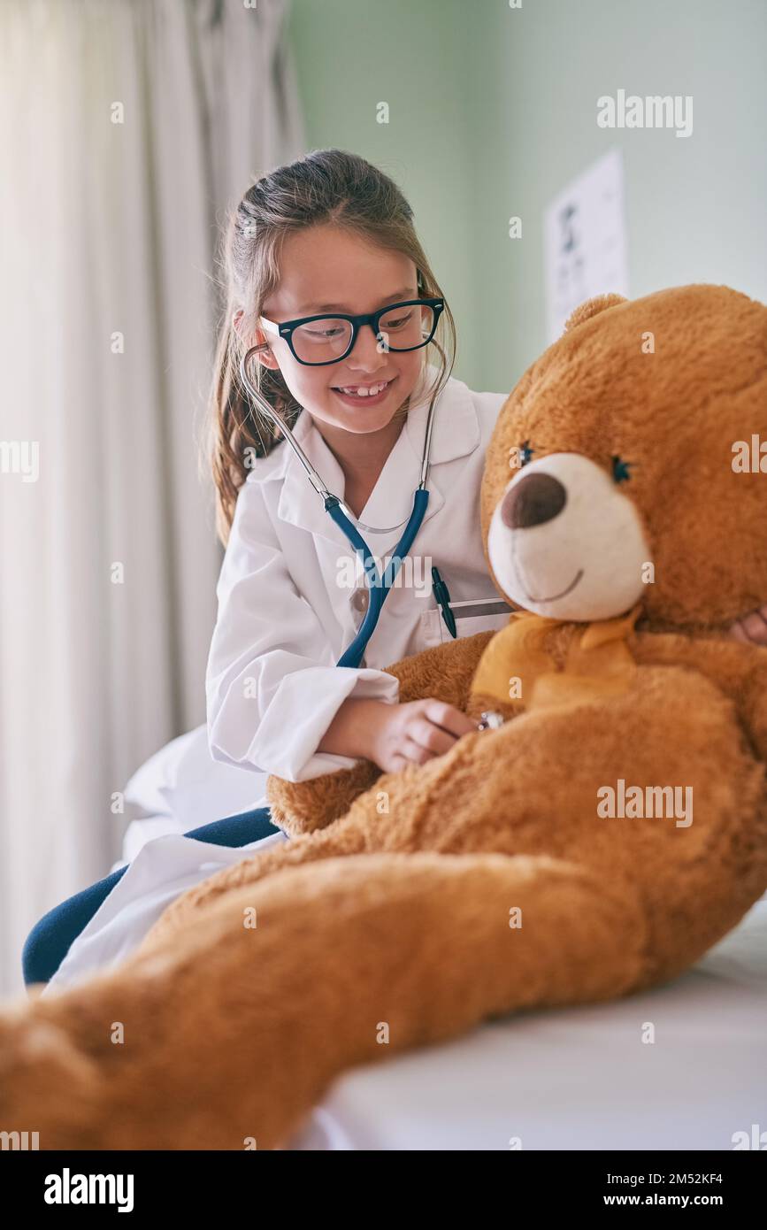 So esattamente cosa aspettarmi al mio prossimo controllo. una bambina che finge di essere un medico mentre esamina il suo orsacchiotto. Foto Stock