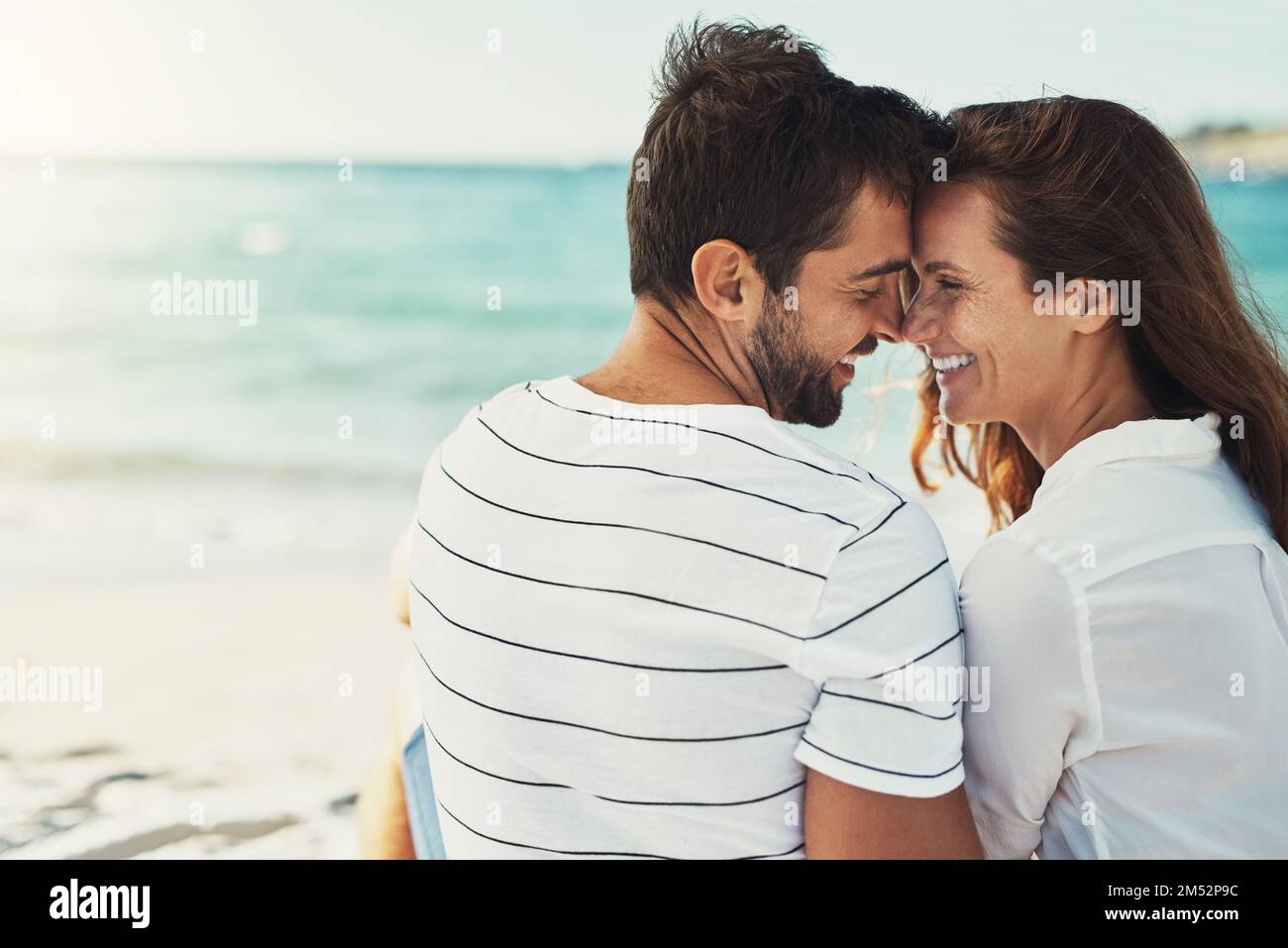 Baci per costruire un sogno estivo su. Ripresa di una giovane coppia che bacia in una giornata estiva in spiaggia. Foto Stock