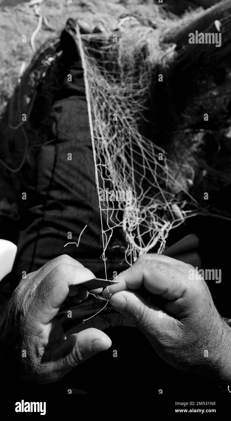 rete da pesca nelle mani di un pescatore, con ago e filo, fotografia in bianco e nero Foto Stock