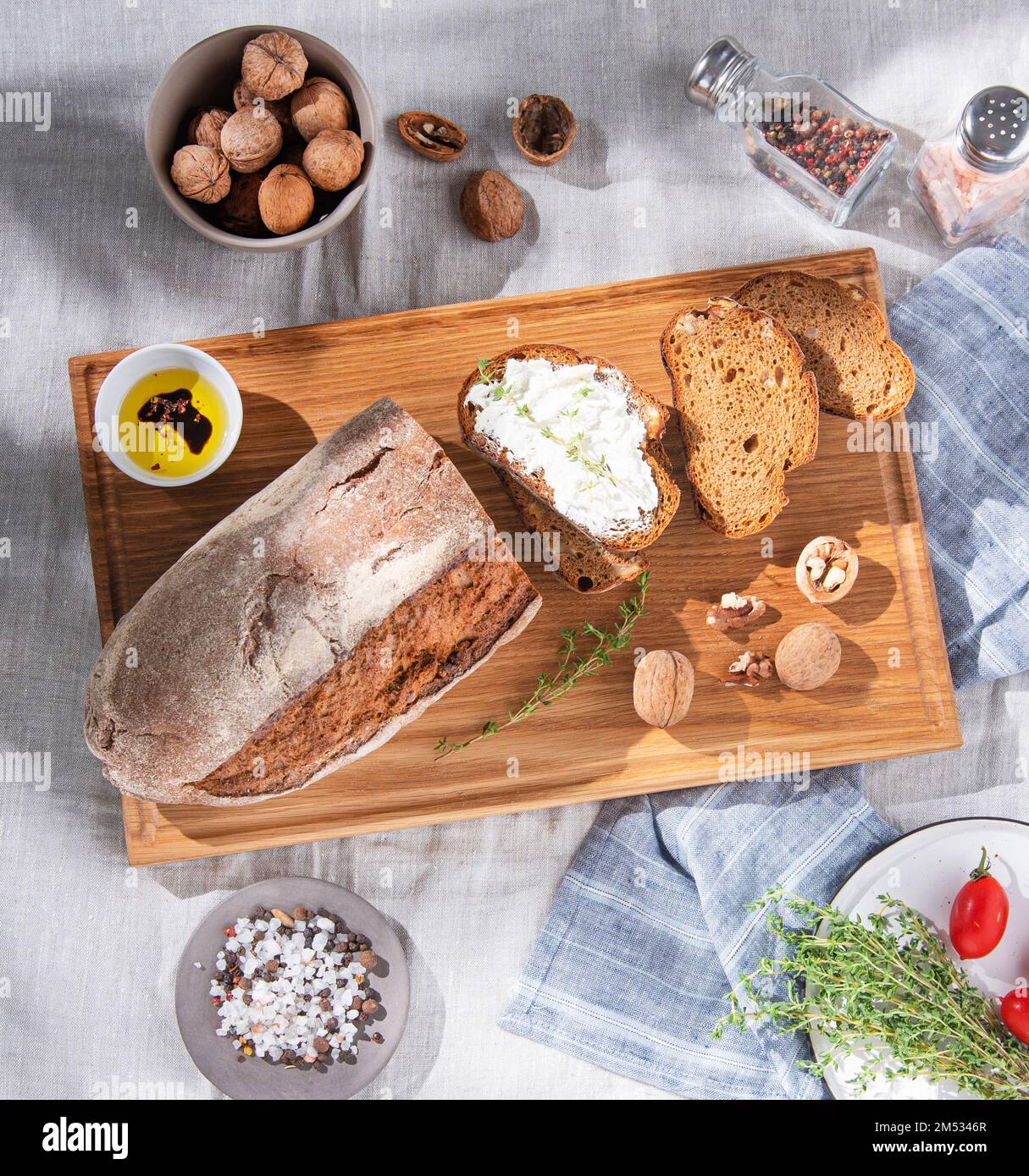 Pane di segale con noci, formaggio morbido e pomodori freschi su un tagliere. Il concetto di una colazione sana. Vista dall'alto. Foto Stock