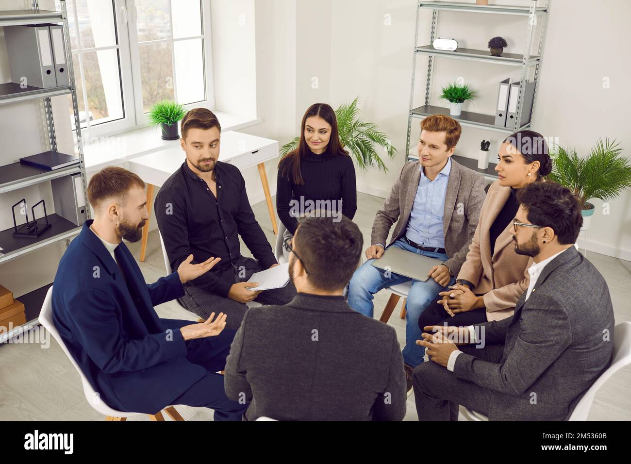 Leader maschile che parla con un gruppo di lavoratori in ufficio, brainstorming, discutere la strategia aziendale. Foto Stock