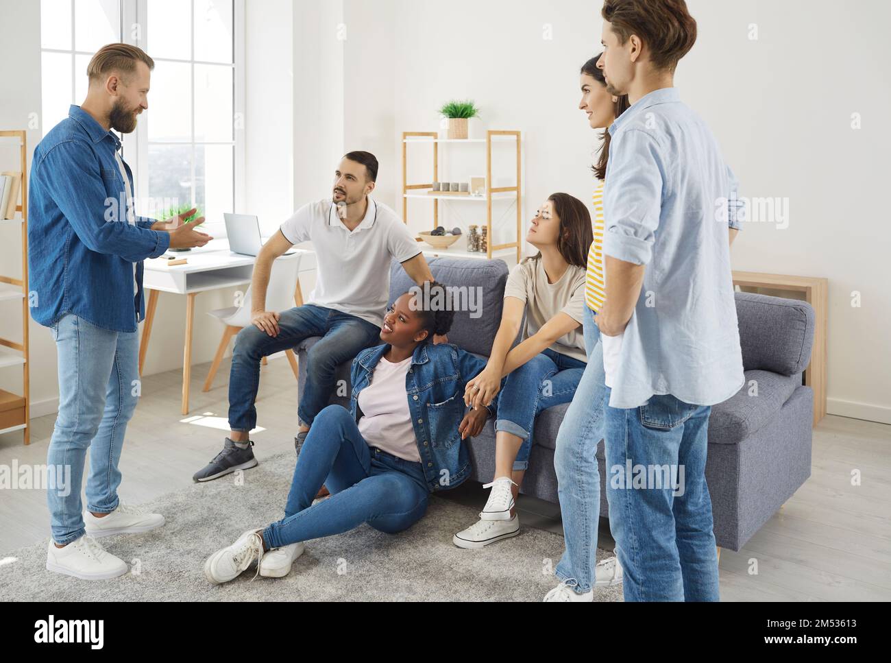 Gruppo di giovani amici a casa in soggiorno con vivace conversazione durante il fine settimana di riunione. Foto Stock