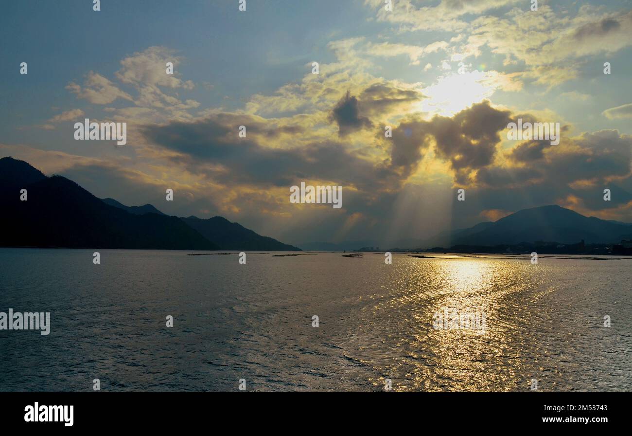 Tramonto a Hiroshima Bay, Seto Inland Sea, tra l'isola di Itsukushima e la città di Hatsukaichi. Prefettura di Hiroshima, Giappone. Foto Stock