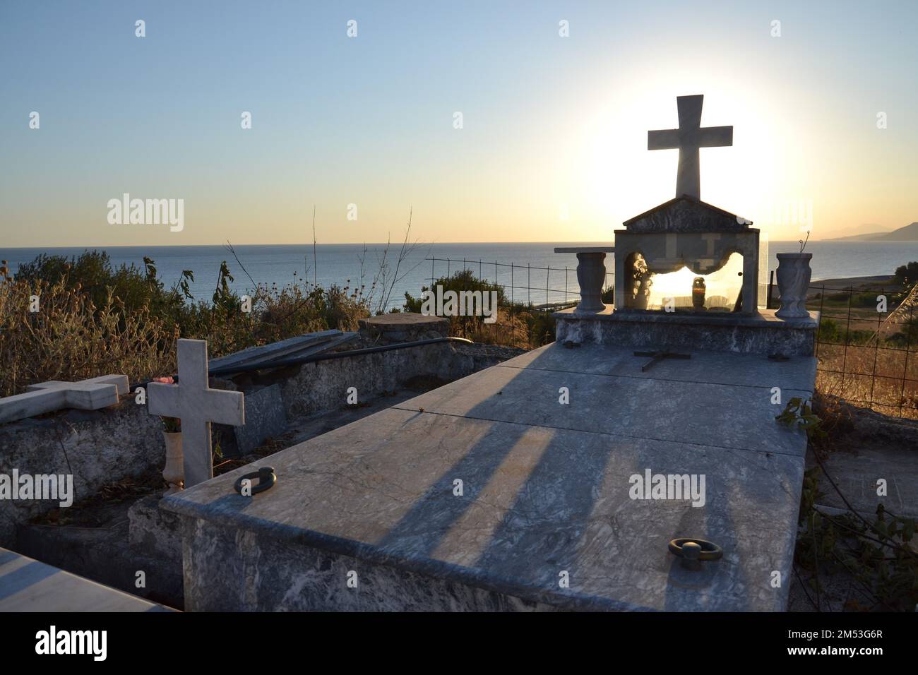 Croce su una tomba in un cimitero greco all'alba Foto Stock