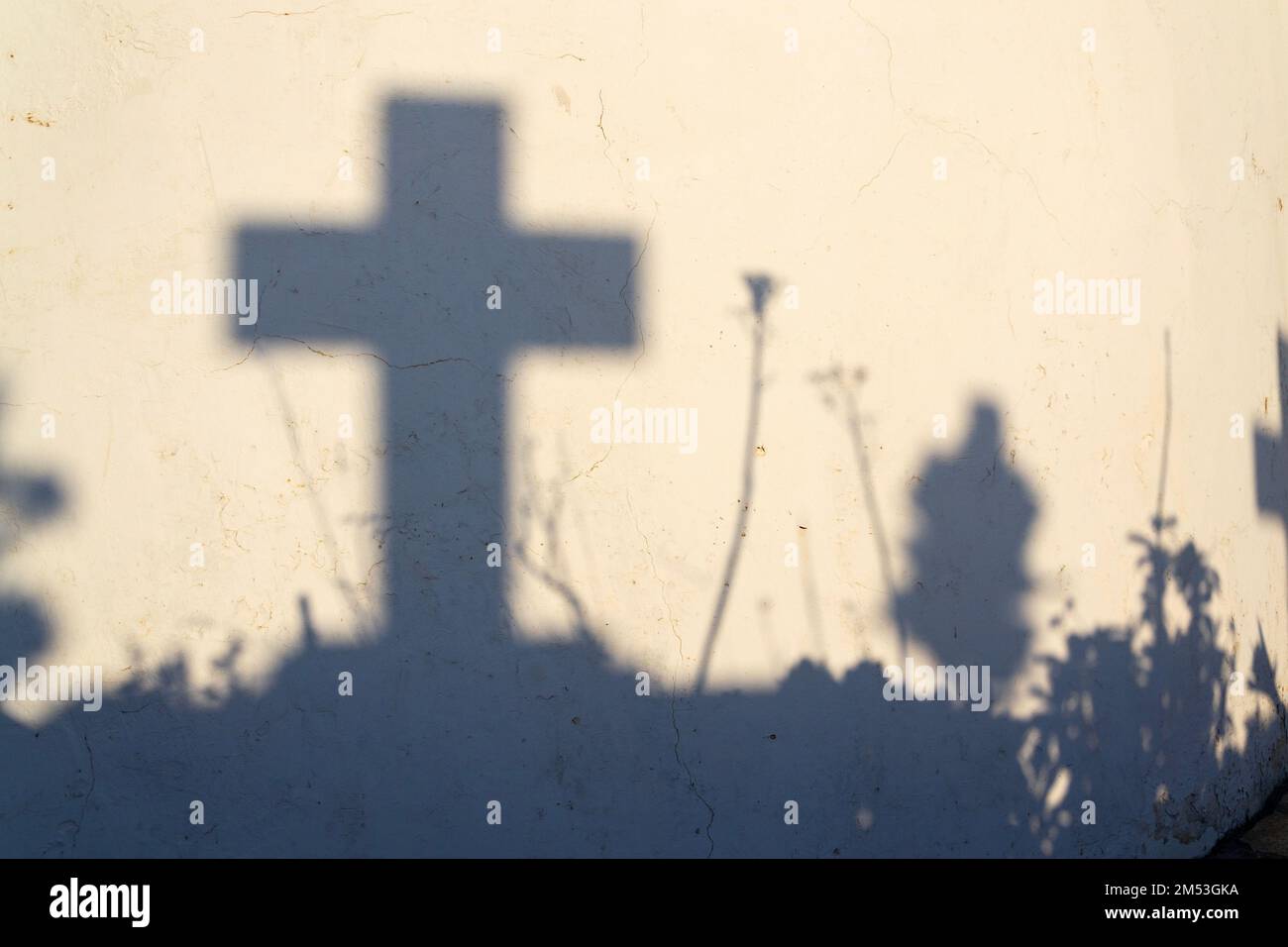 Ombra di una croce su una tomba in un cimitero greco all'alba Foto Stock