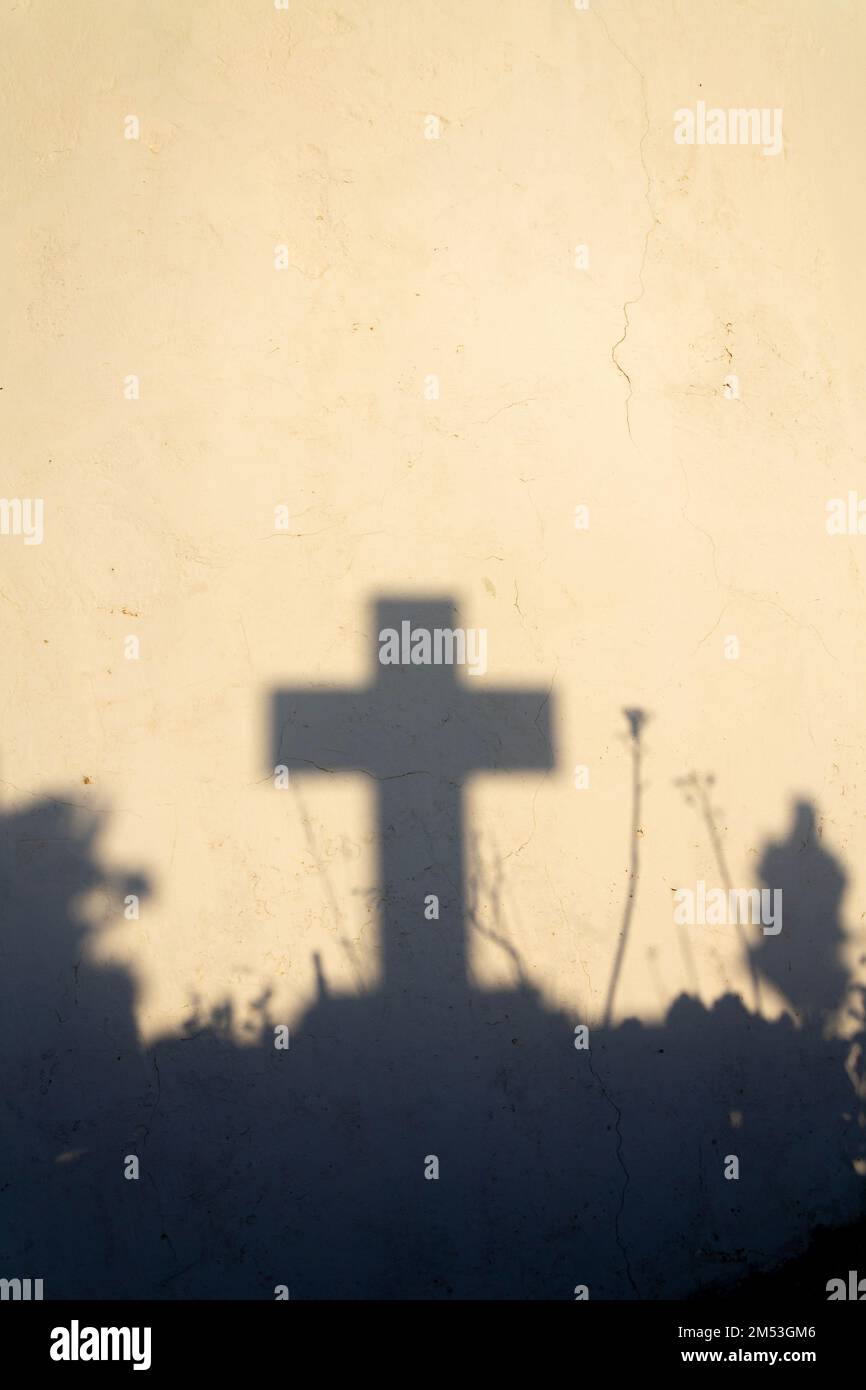 Ombra di una croce su una tomba in un cimitero greco all'alba Foto Stock