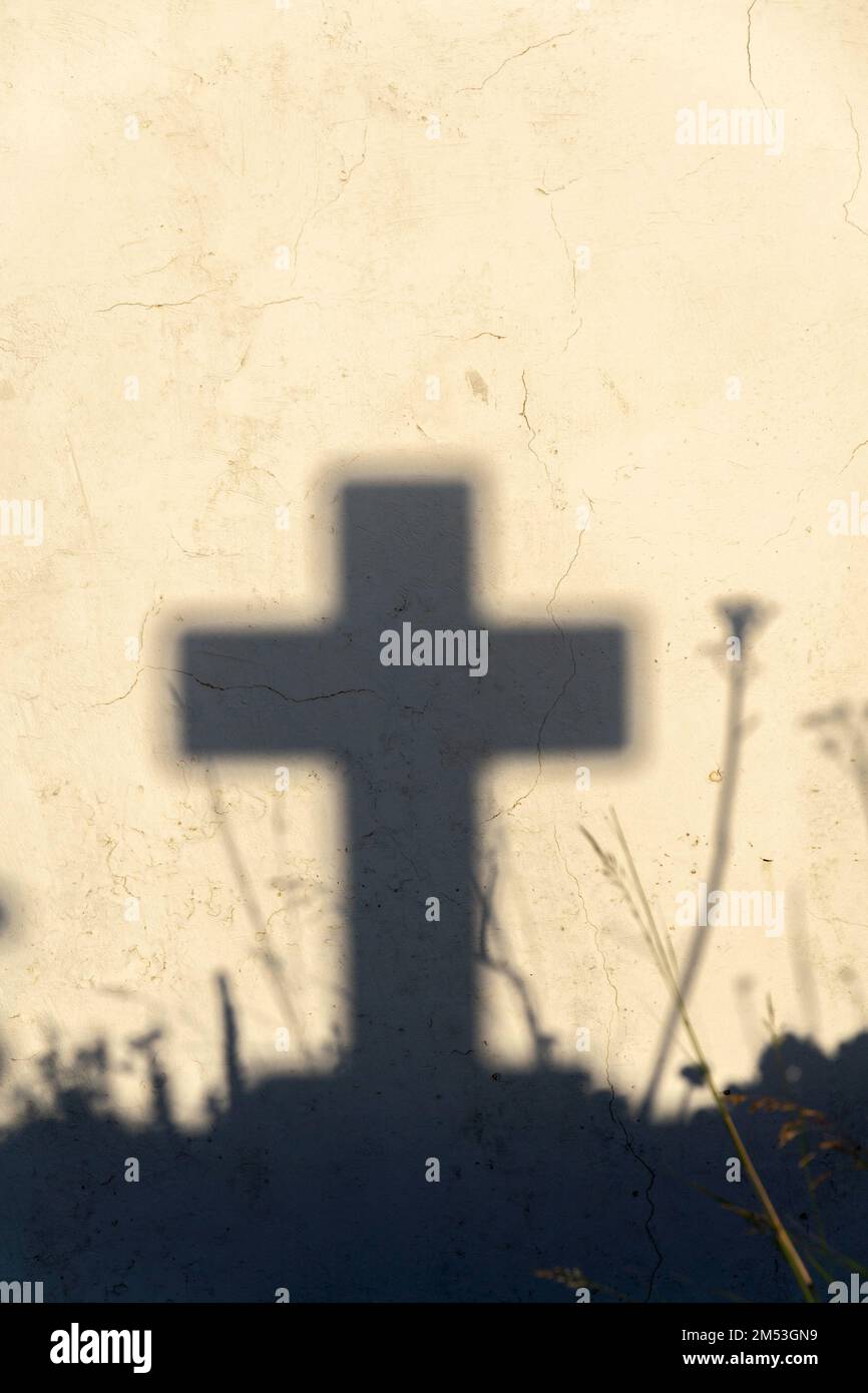 Ombra di una croce su una tomba in un cimitero greco all'alba Foto Stock
