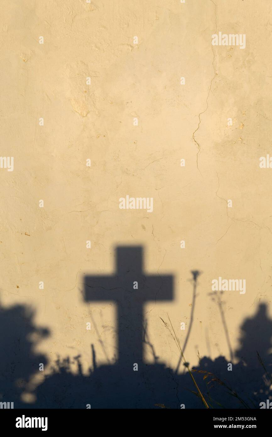 Ombra di una croce su una tomba in un cimitero greco all'alba Foto Stock