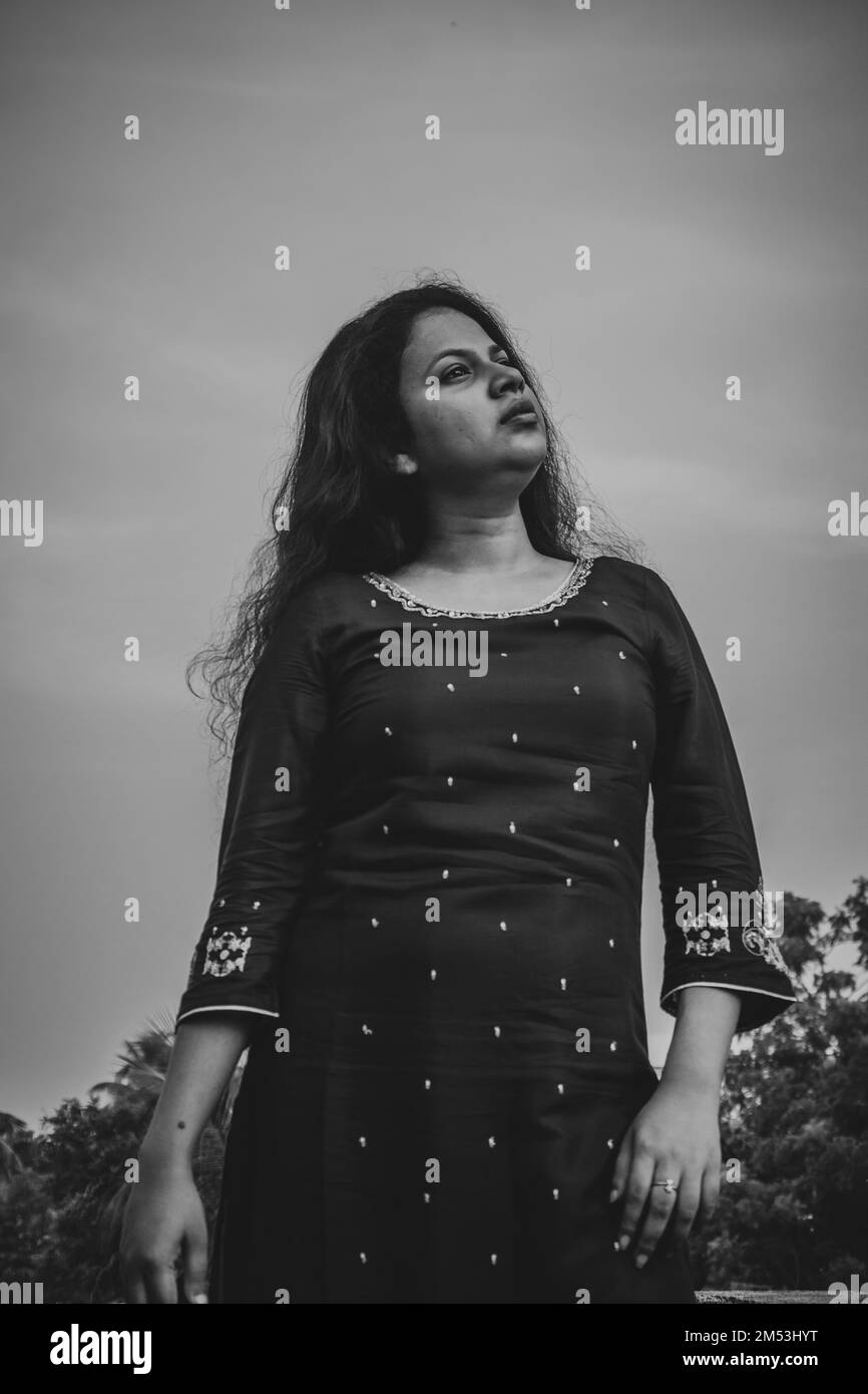 Un tiro verticale in scala di grigi con angolo basso di una donna indiana che indossa un abito tradizionale Foto Stock