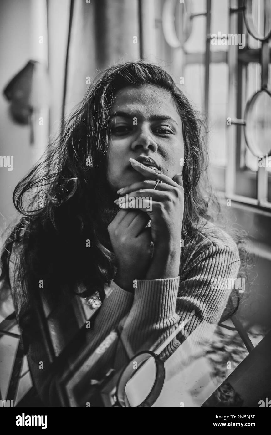 Un ritratto in scala di grigi di una donna indiana attraente seduta e guardare dritto Foto Stock