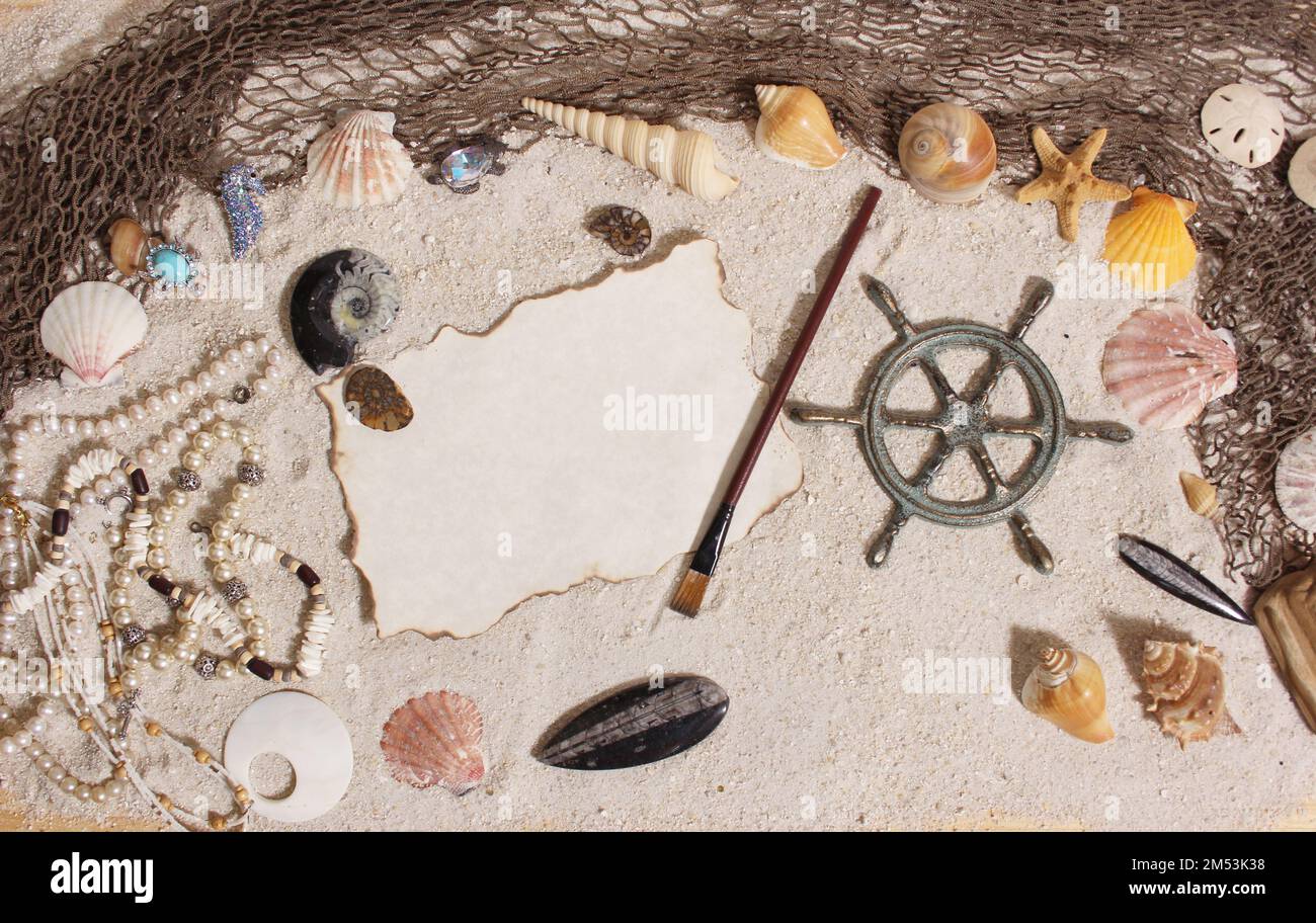 Una vista dall'alto della ruota dei Captains con rete da pesca e conchiglie di mare sulla sabbia Foto Stock