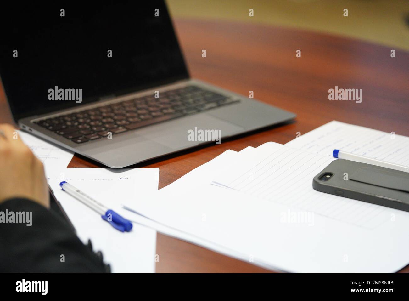 Una persona professionista in una riunione sta scrivendo o prendendo appunti su carta con il portatile aperto. una persona sta studiando duro. Foto Stock