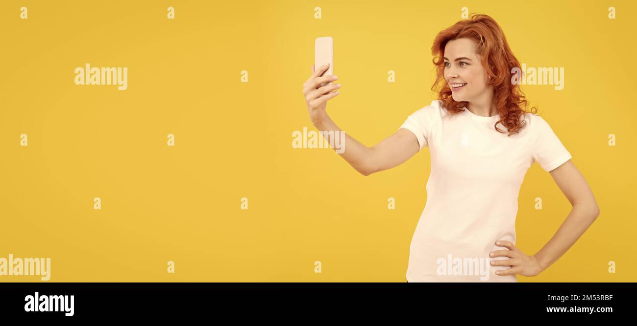 Felice ragazza sorriso a cellulare fotocamera sfondo giallo, selfie video. Donna isolato volto ritratto, banner con mock up spazio copia. Foto Stock