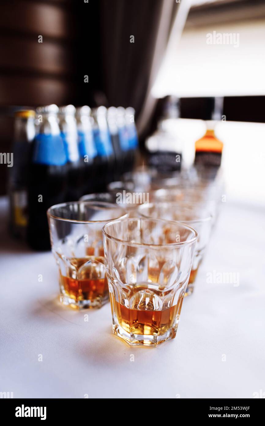 molti bicchieri con cognac, brandy o whisky stand al bar. Varie bevande alcoliche in bicchieri durante la festa. Foto Stock