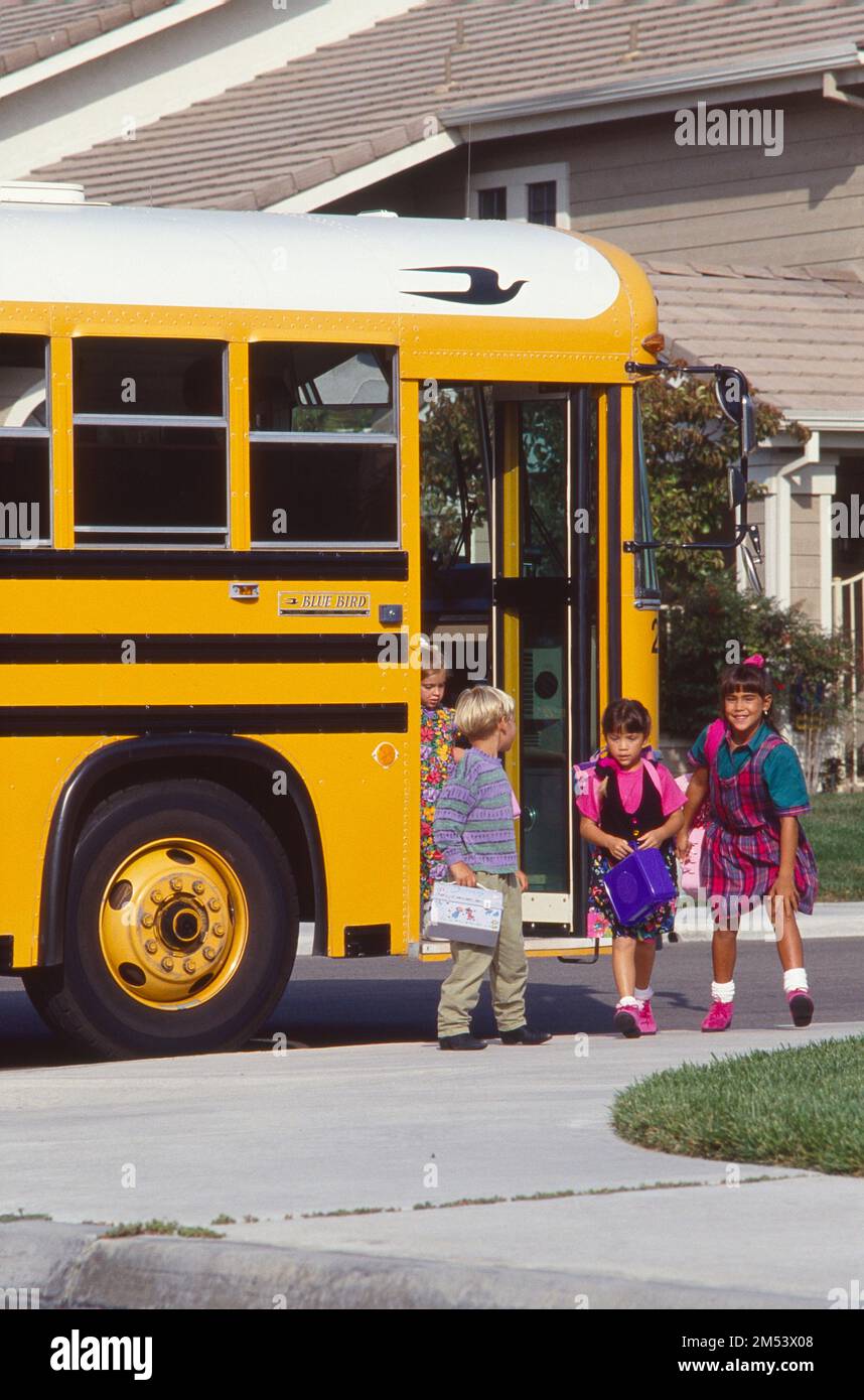 Bambini in età scolare che scendano dal bus scolastico a casa Foto Stock