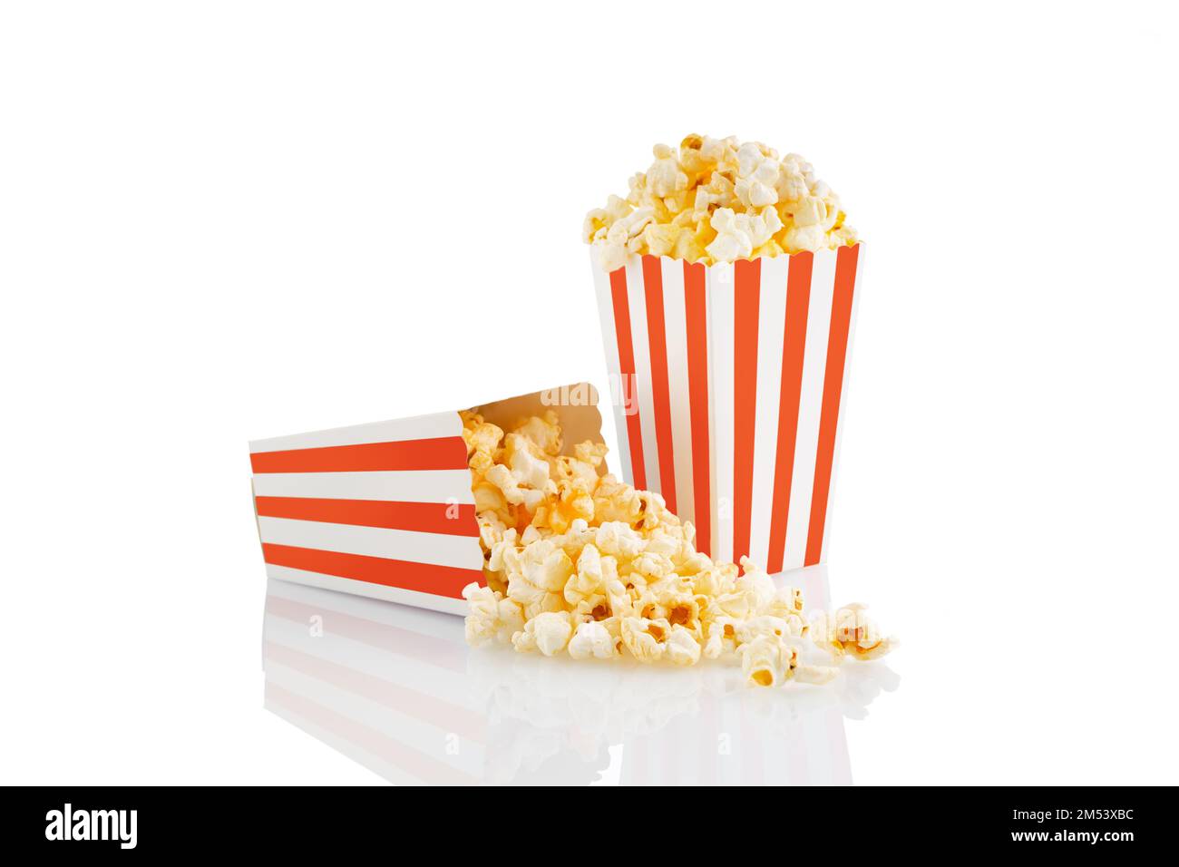 Due secchi in cartone a strisce bianche rosse con gustosi popcorn al formaggio, isolati su sfondo bianco. Scatola con dispersione di grani di popcorn. Film, cinema e. Foto Stock
