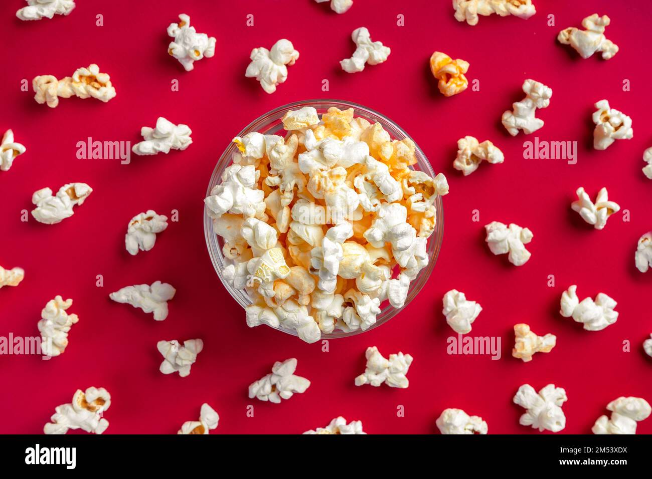 Formaggio saporito popcorn sparso in ciotola isolato su sfondo rosso. Sfondo, banner, intestazione con spazio di copia per il testo Foto Stock