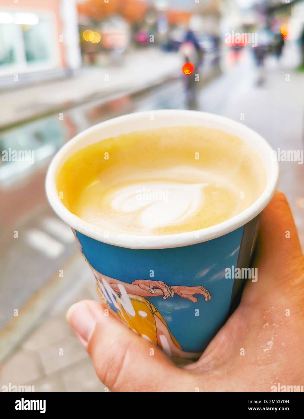 La mano di una donna tiene una tazza di carta a colori di caffè caldo per andare, take away, concetto di grande città, foto d'archivio Foto Stock