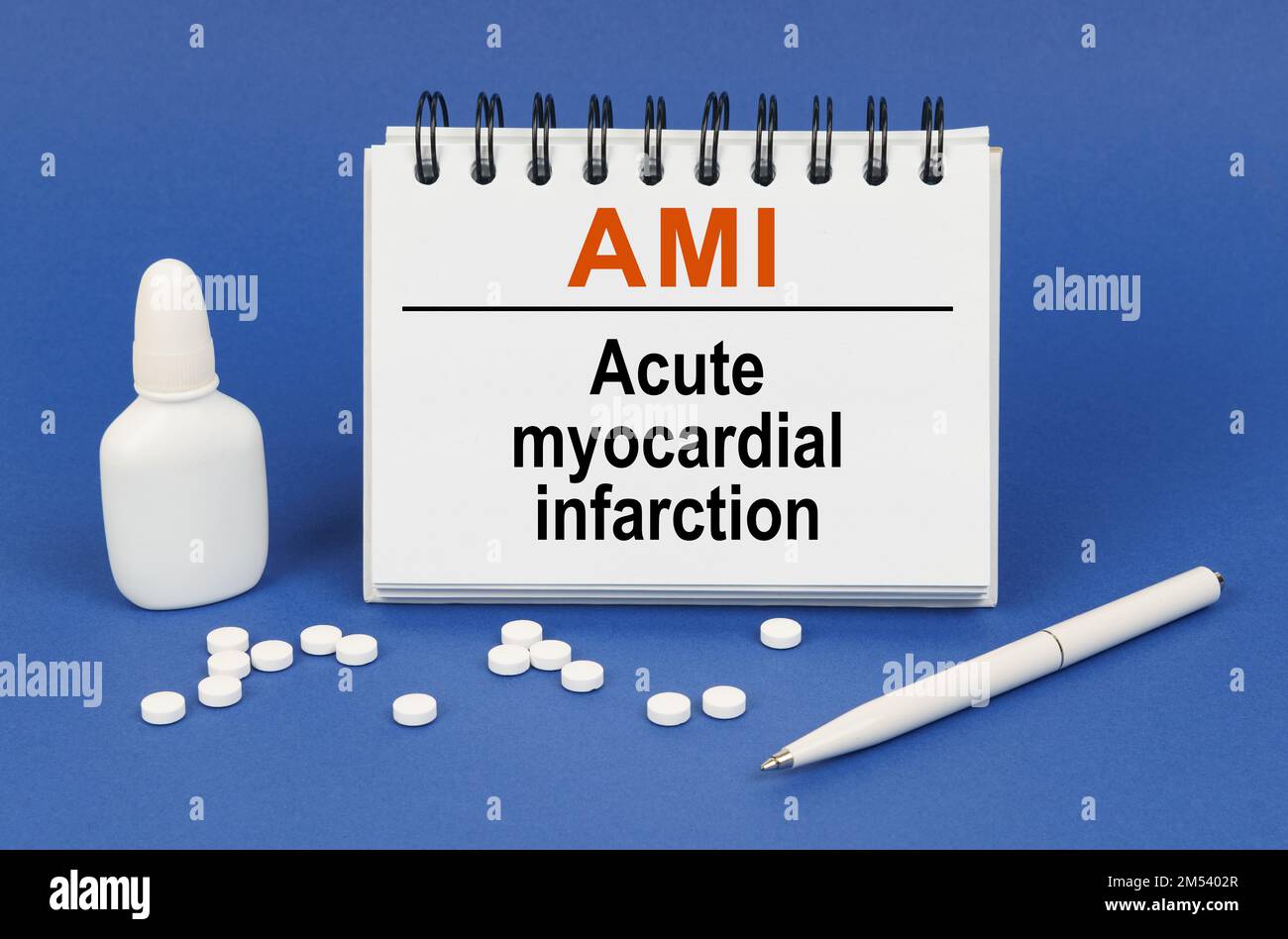 Concetto medico. Su sfondo blu, una penna, compresse e un blocco note con la scritta: Infarto miocardico acuto AMI Foto Stock