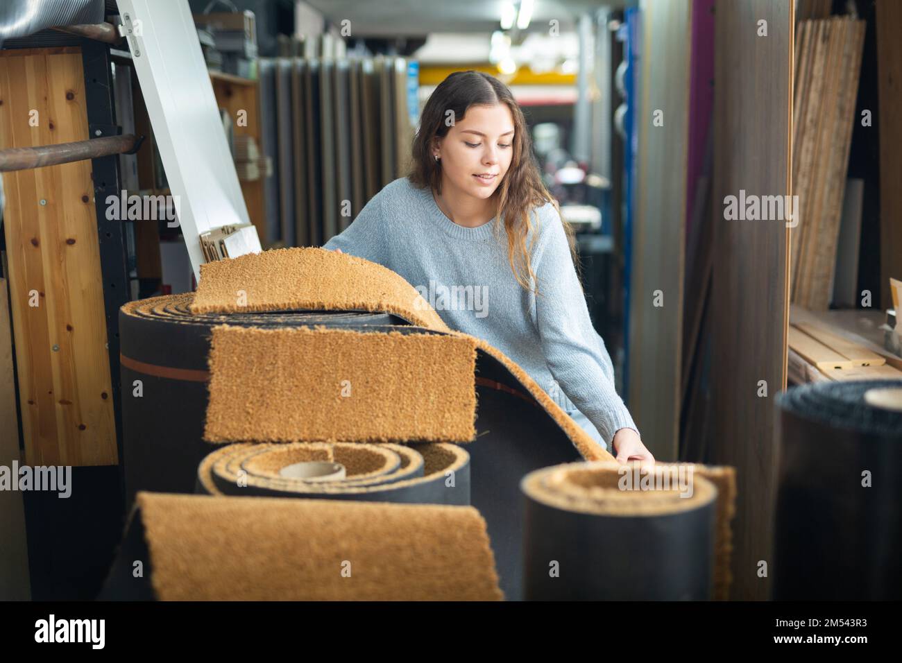 Donna che sceglie i campioni di pavimentazione nell'ipermercato di costruzione Foto Stock