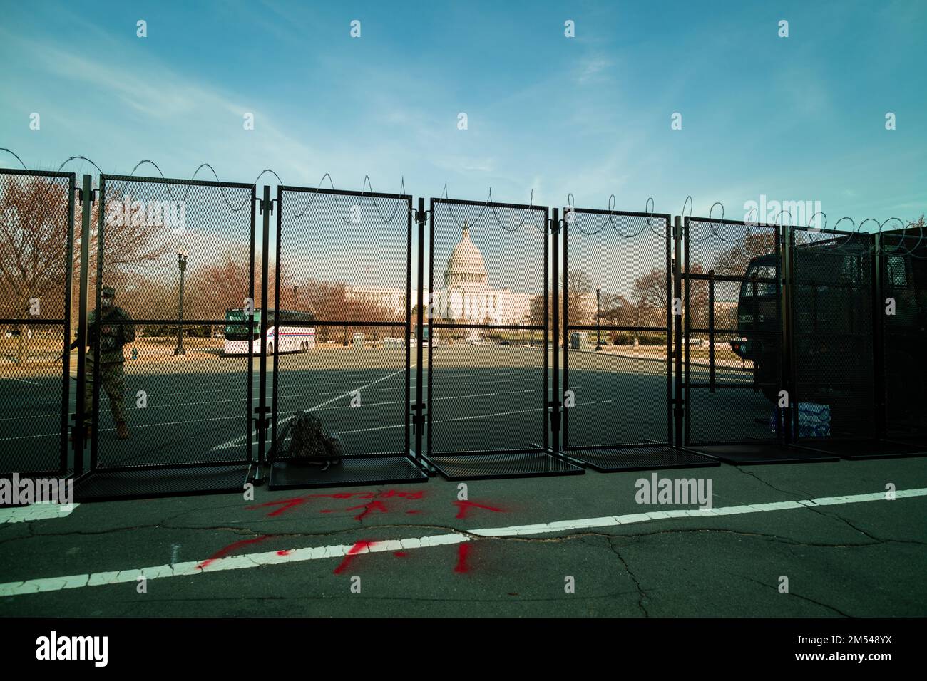 Un soldato della Guardia Nazionale è in piedi guardia presso gli Stati Uniti Edificio del Campidoglio a Washington, DC. al tramonto, fortificata dietro una recinzione di metallo sormontata da filo di rasoio Foto Stock