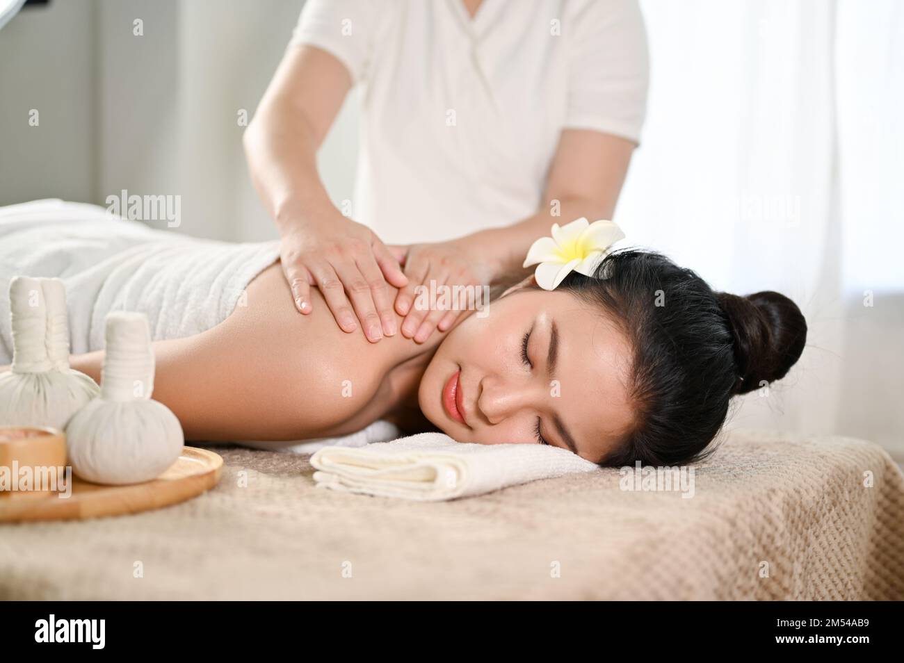 Affascinante e rilassante giovane donna asiatica che ottiene il massaggio  di schiena e spalle sul tavolo di massaggio da un massaggiatore tailandese  professionale. Trattamento corpo, benessere, noi Foto stock - Alamy
