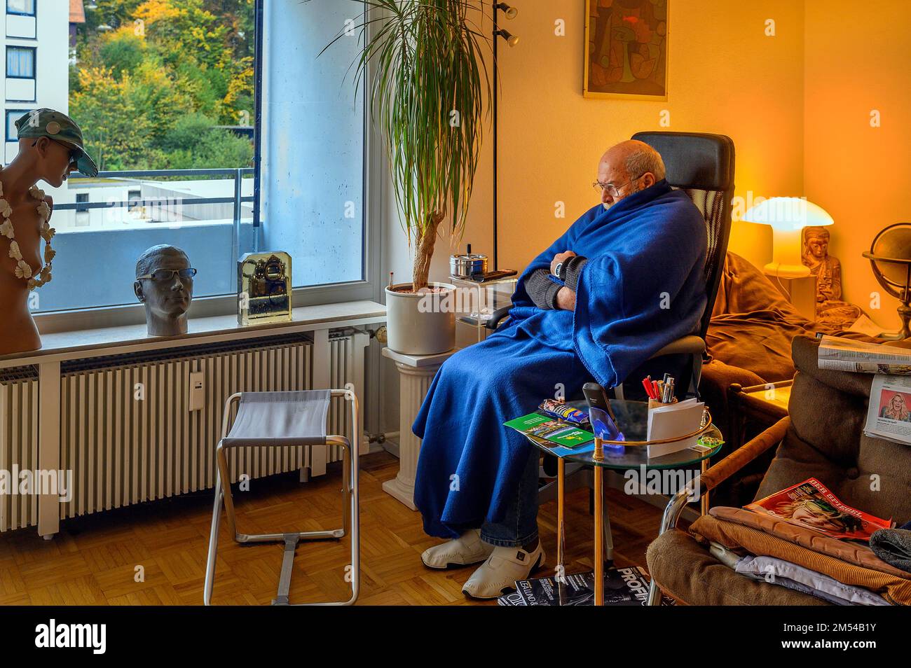 Vecchio avvolto in coperte, risparmiare energia, congelare a causa di Putin, risparmiare costi di riscaldamento, bassa temperatura ambiente, Baviera, Germania Foto Stock