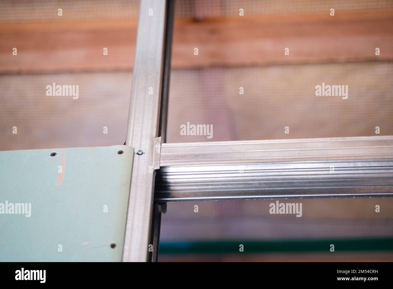 L'inizio del processo di rivestimento del telaio con muro a secco. Un foglio di cartongesso resistente all'umidità è avvitato a un profilo metallico in primo piano Foto Stock