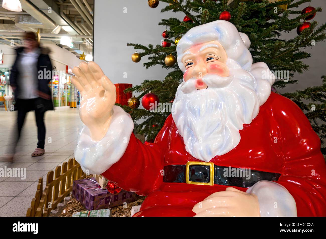 Babbo Natale che sventura ai passanti, Babbo Natale di fronte all'albero di Natale decorato, figura di plastica, decorazione di Natale in supermercato Foto Stock