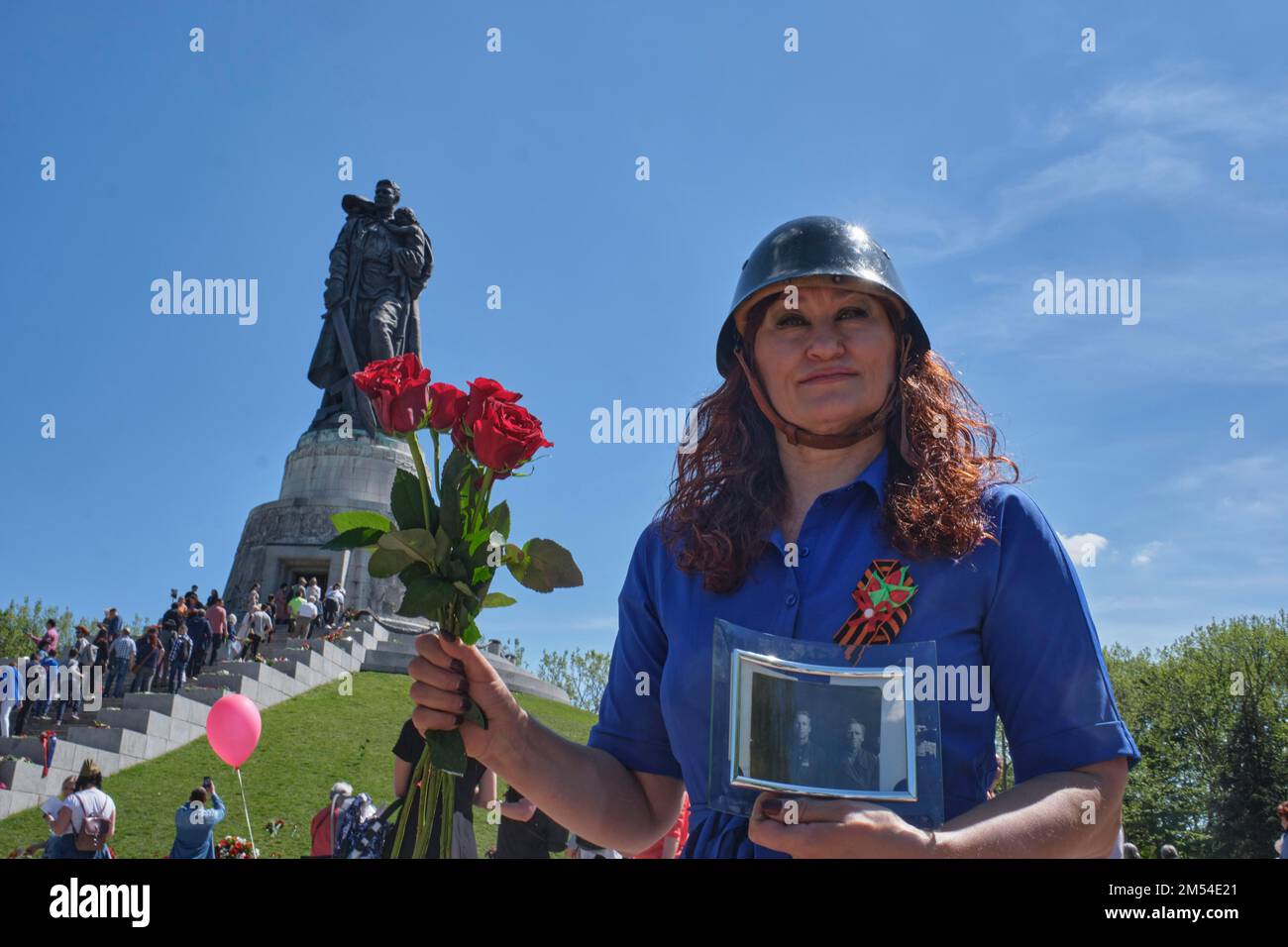 Germania, Berlino, 09. 05. 2020, Giornata della Vittoria (oltre il fascismo di Hitler), Memoriale sovietico Berlino-Treptow, donna con casco in acciaio, rose e commemorativo Foto Stock