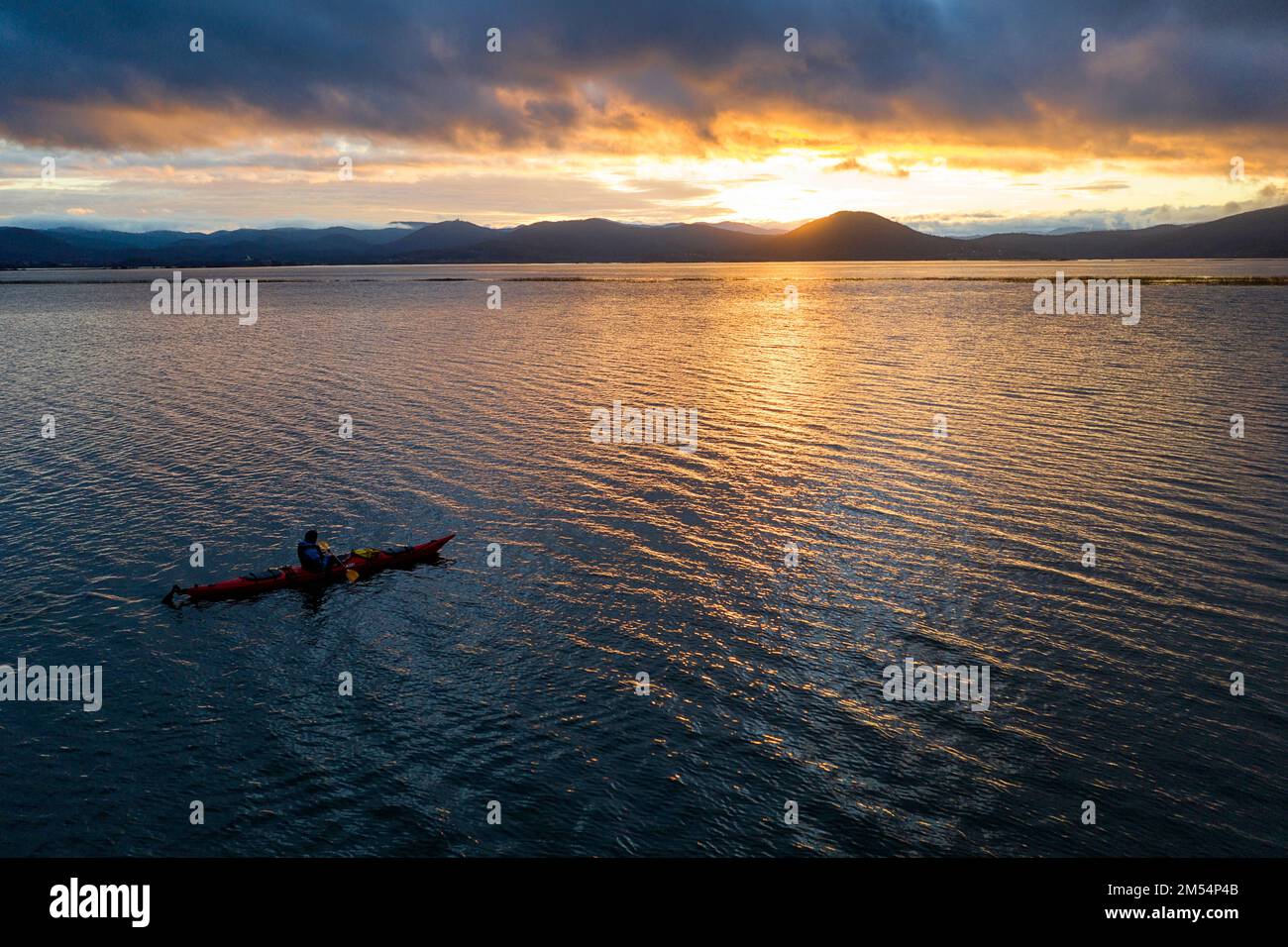 Vista aerea di un uomo locale in kayak godendosi su una bella alba in una fredda mattina d'inverno, mentre pagaia sul lago intermittente in slovenia Foto Stock