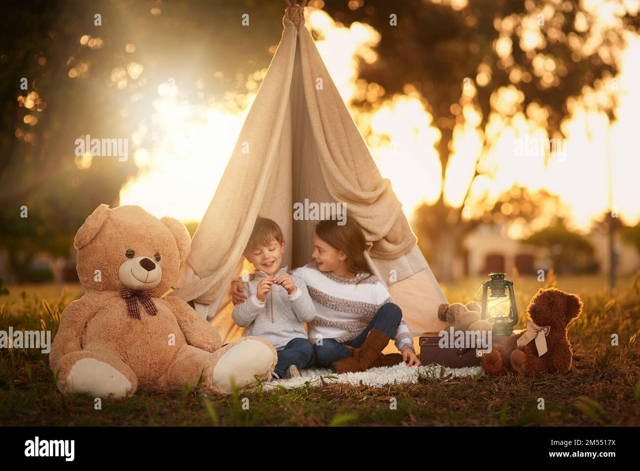 I migliori giochi sono quelli che giochi insieme. due piccoli fratelli carini che giocano insieme in un teepee fuori. Foto Stock