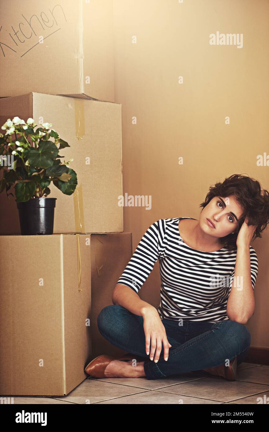 Ti lascerai un sacco di ricordi. una giovane donna seduta sul pavimento e che guarda triste nel giorno in movimento. Foto Stock