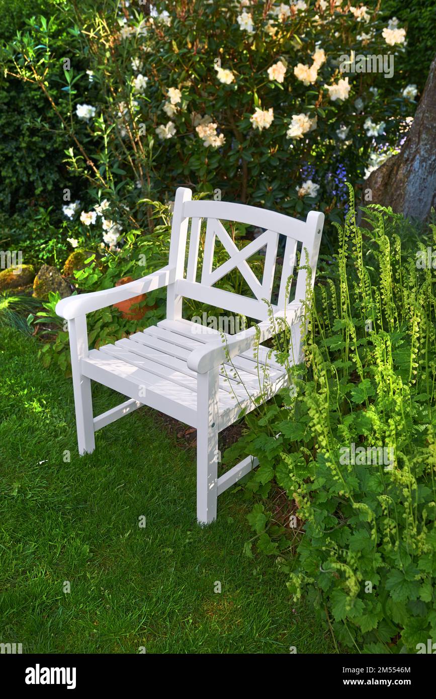 Primavera in giardino. Giardino con sedia bianca in primavera. Foto Stock