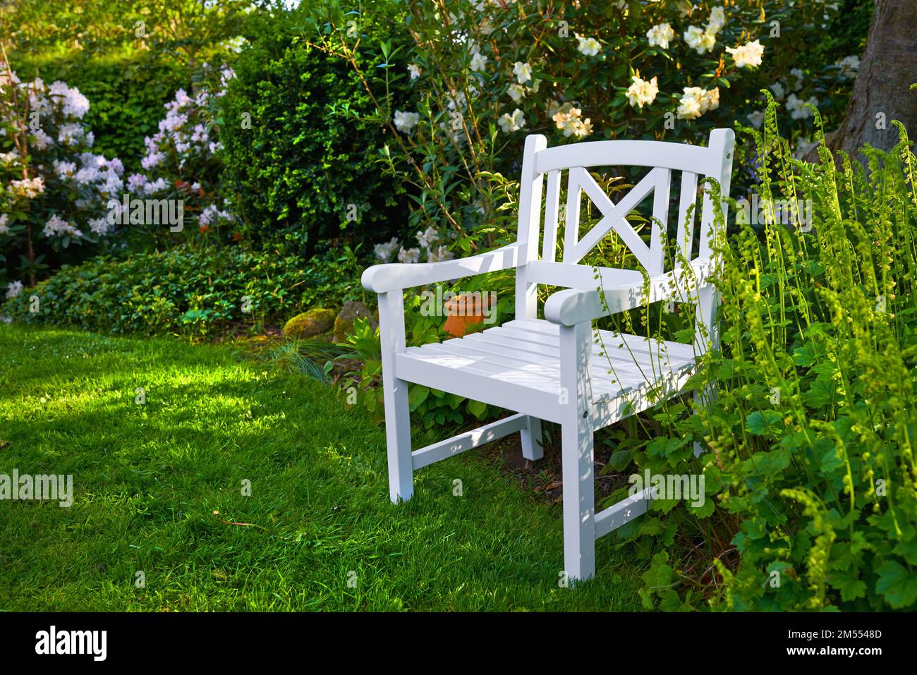 Primavera in giardino. Giardino con sedia bianca in primavera. Foto Stock