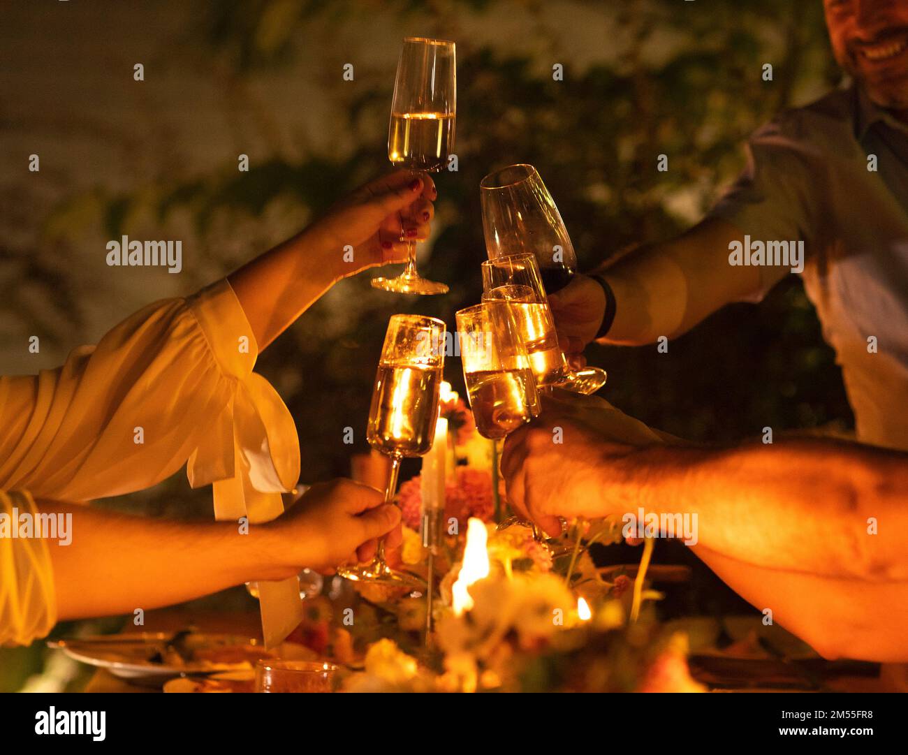 Amici felici che si acclamano e che mostrano i loro bicchieri di champagne pieni di spumante l'uno all'altro mentre si godono una festa di nozze all'aperto su un bac Foto Stock