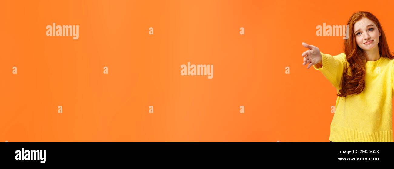 Ragazza chiedendo a venire qui a dare Cheer up abbraccio. Carino e toccò la gara redhead donna in felpa gialla, estendono bracci,allungare le mani avanti per coccolare Foto Stock