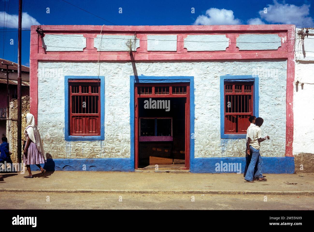 Etiopia, 1970s, Harar, 2 uomini e donne che camminano di fronte a una casa di colore rosa bianco e blu, regione di Harari, Africa orientale, Foto Stock