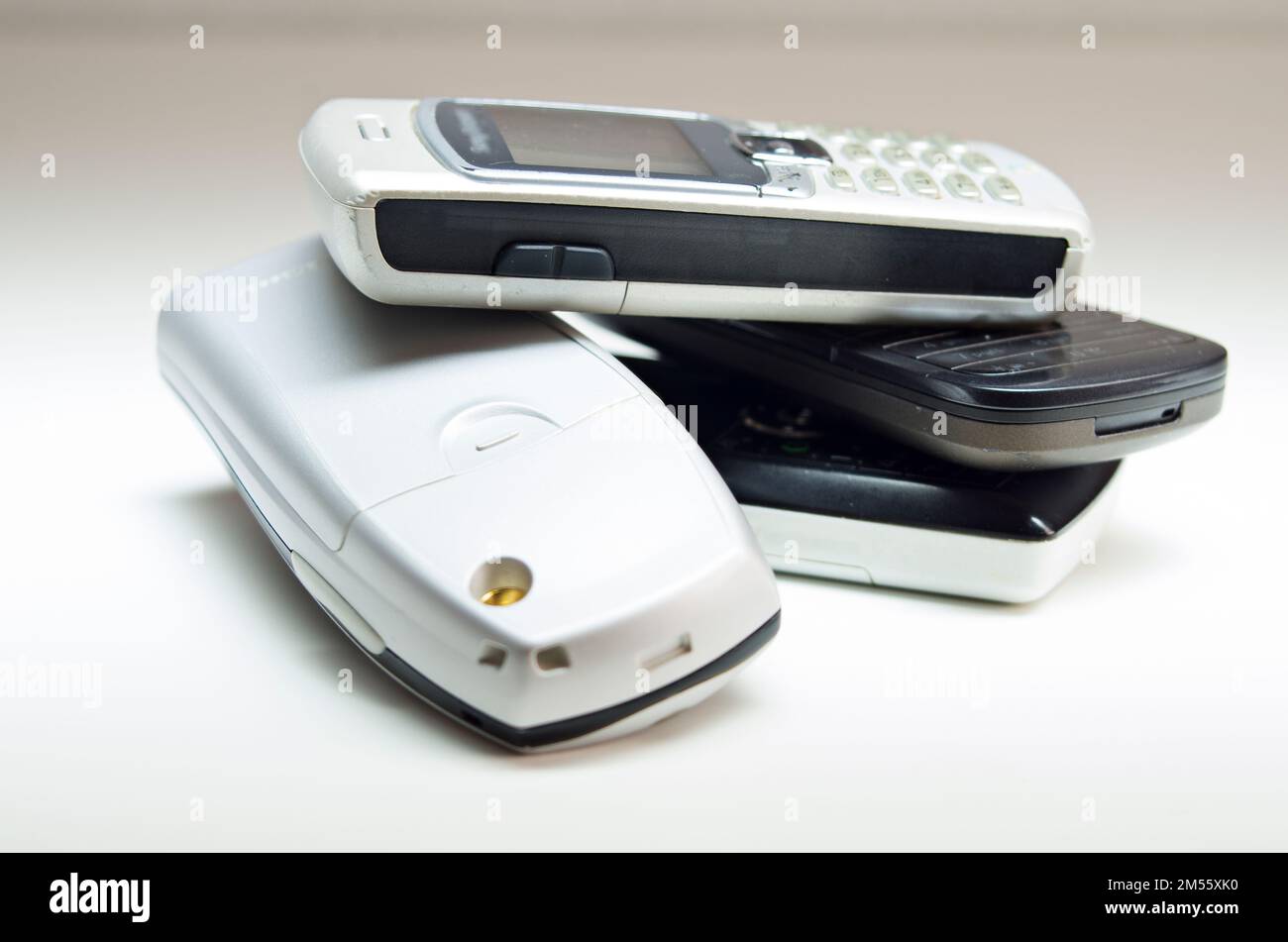 Un primo piano di diversi vecchi telefoni cellulari su una superficie bianca. Foto Stock