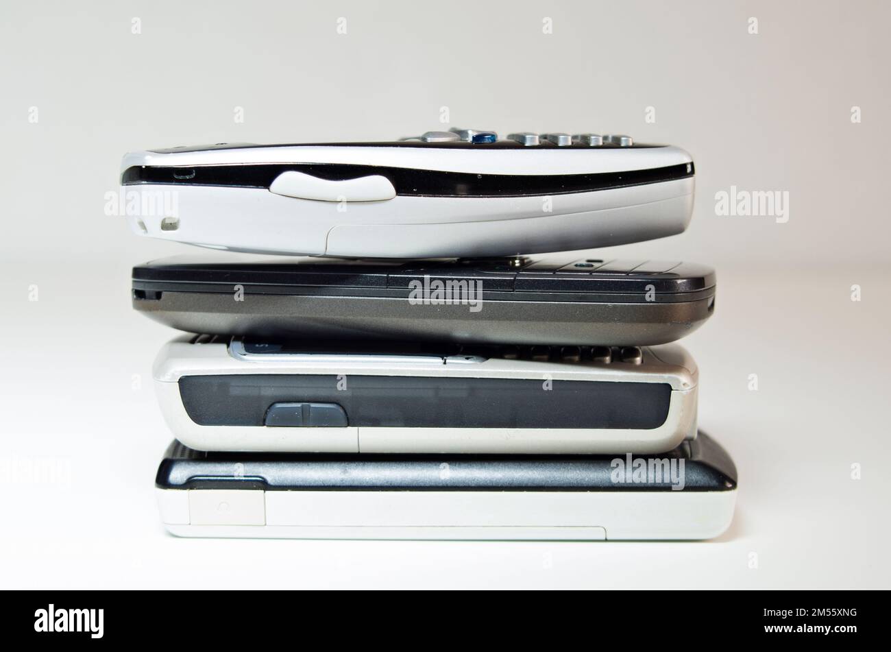 Un primo piano di diversi vecchi telefoni cellulari su uno sfondo bianco. Foto Stock